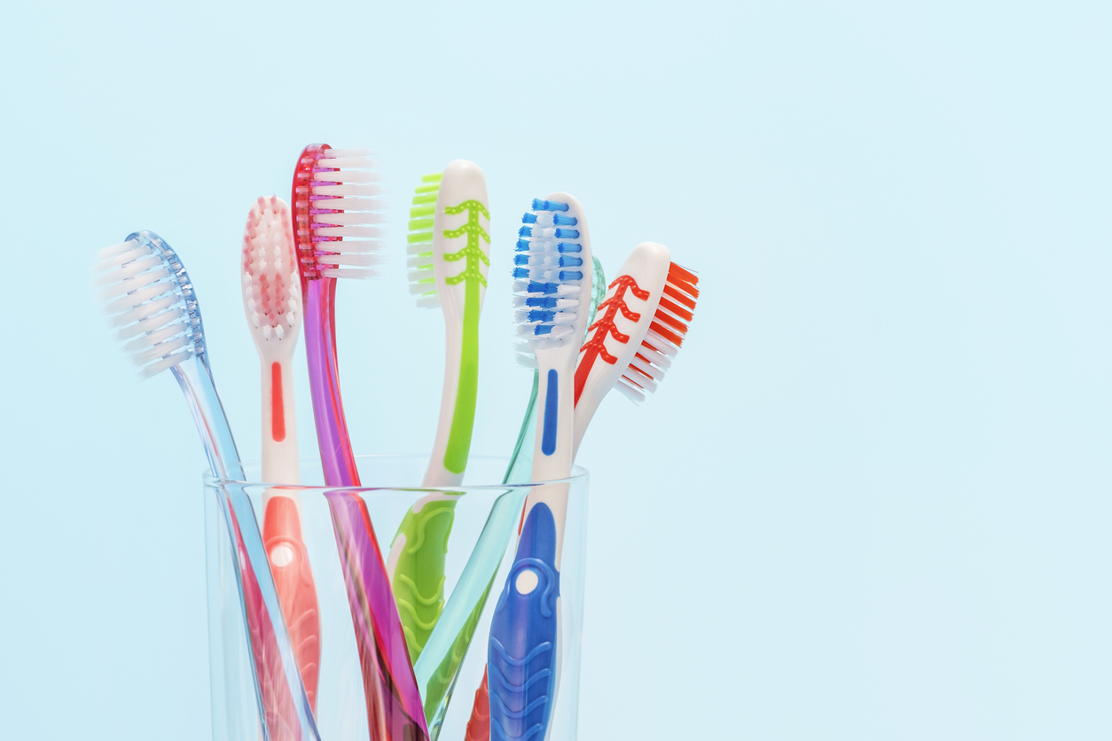 Toothbrushes in glass cup on blue background